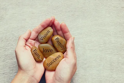 hands holding stones with the words vision, family, love, faith, and success