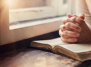 hands folded over bible