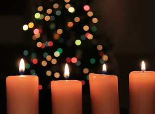 lit candles in front of a Christmas tree